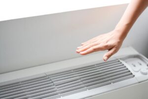 A person is reaching for the air vent.